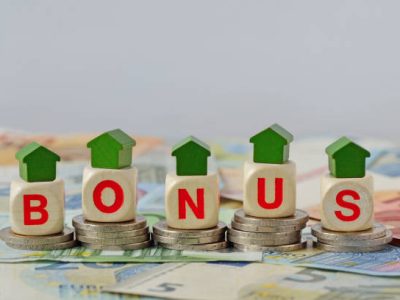 Wooden house and blocks with the word Bonus on coins and banknotes - Concept of home renovation bonus